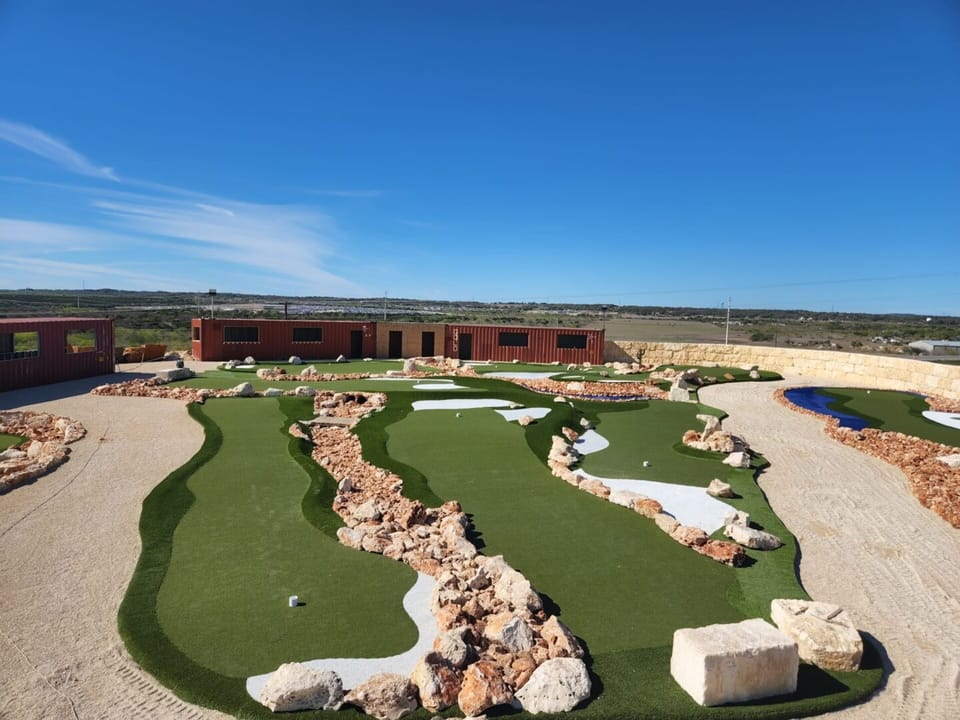 Elevated view of rock lined mini golf holes under deep blue Texas sky
