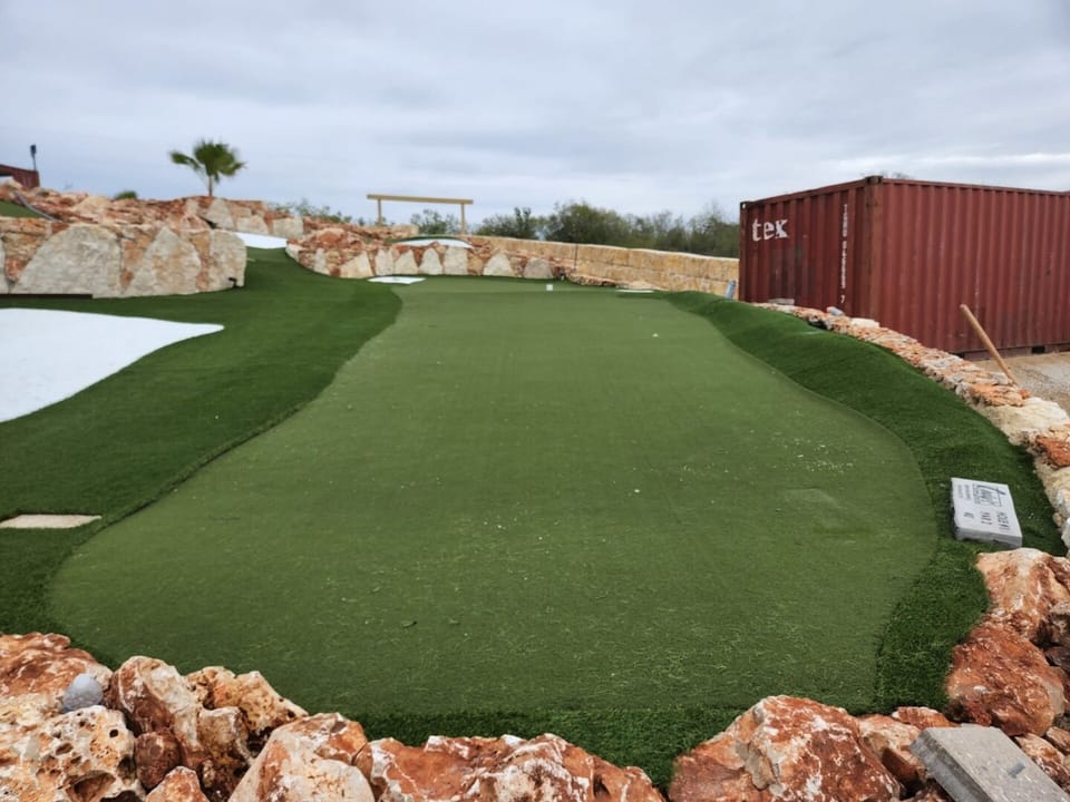 Hole one fairway winding between rust rock borders toward the red clubhouse