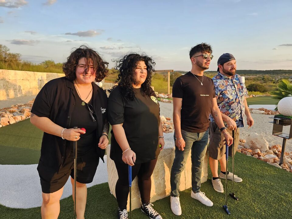 Four friends with putters on the course at golden hour