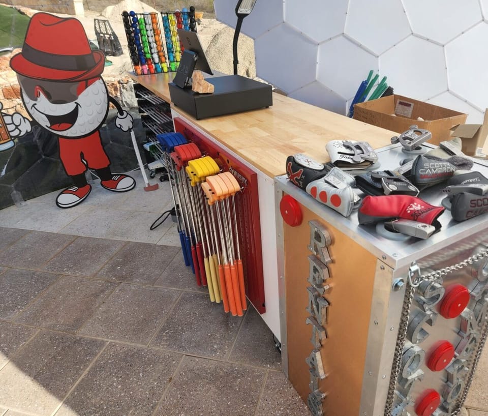 Rental counter stocked with color coded putters and golf balls.